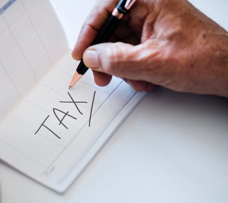 person writing the word TAX
