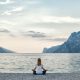 Woman meditating with a lake and mountains in the background