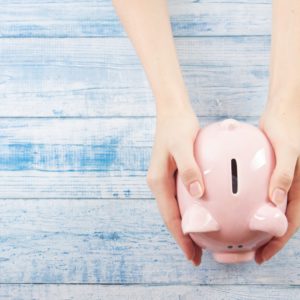 woman holding a piggy bank on a blue wooden table