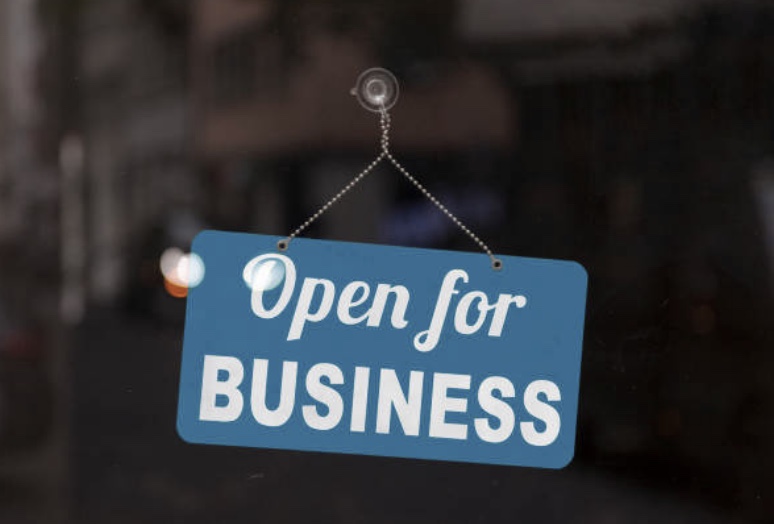 shop window with an open for business sign hanging